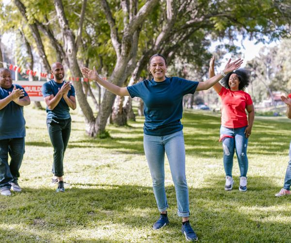 A diverse group of people smiling during an outdoor wellness activity.
